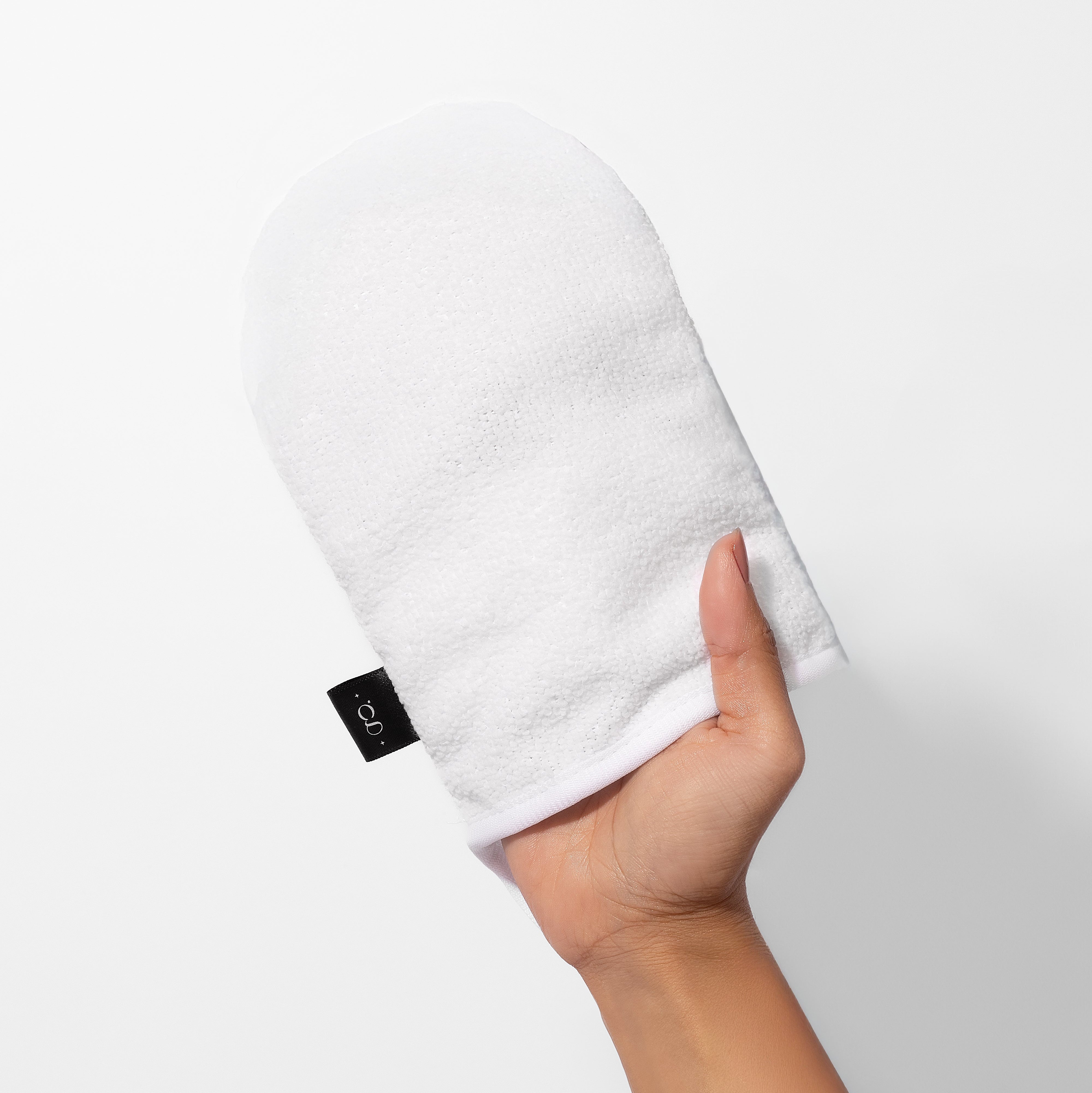 Hand holding a white towel with a black tag on a light gray background