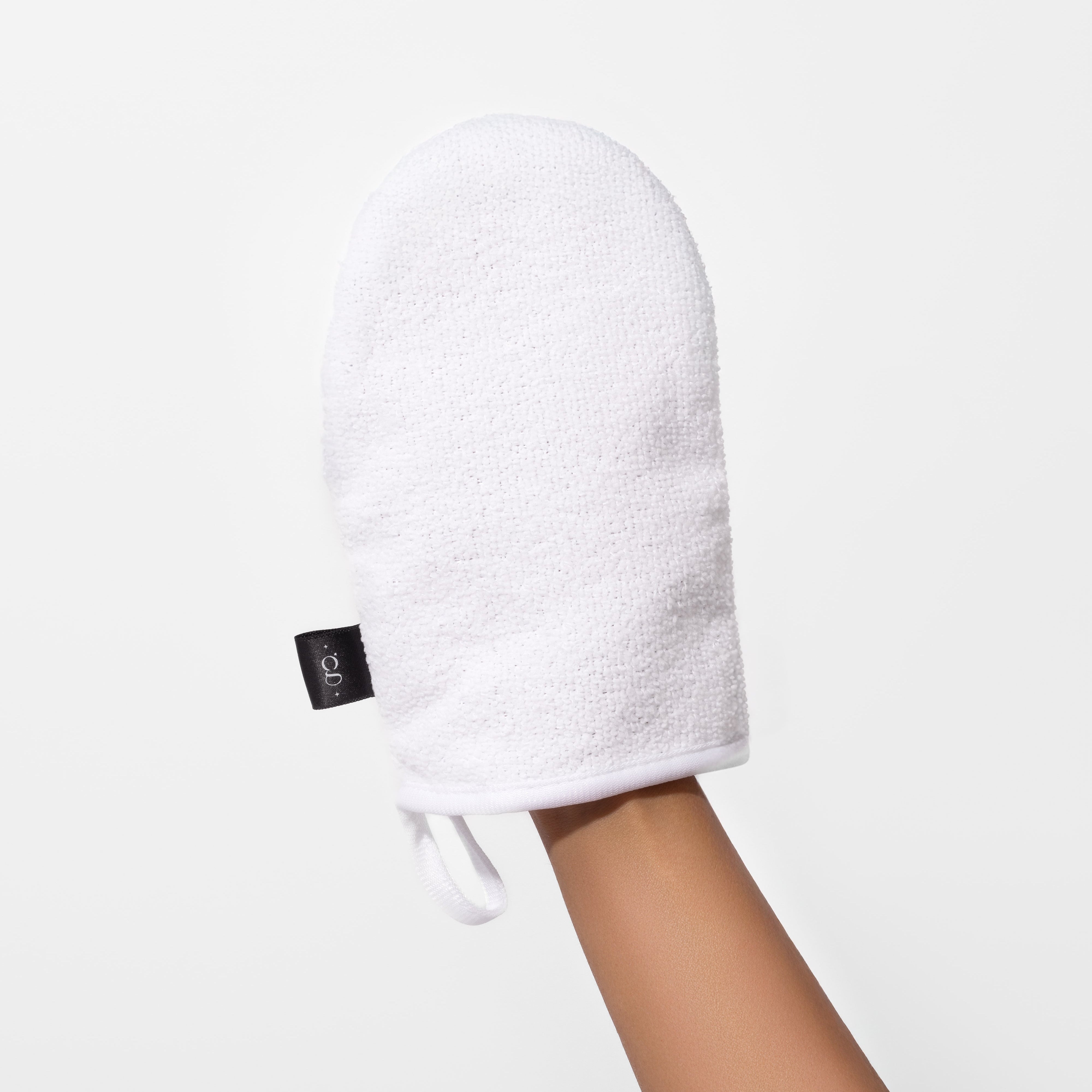 White bath mitt held by a hand on a light gray background